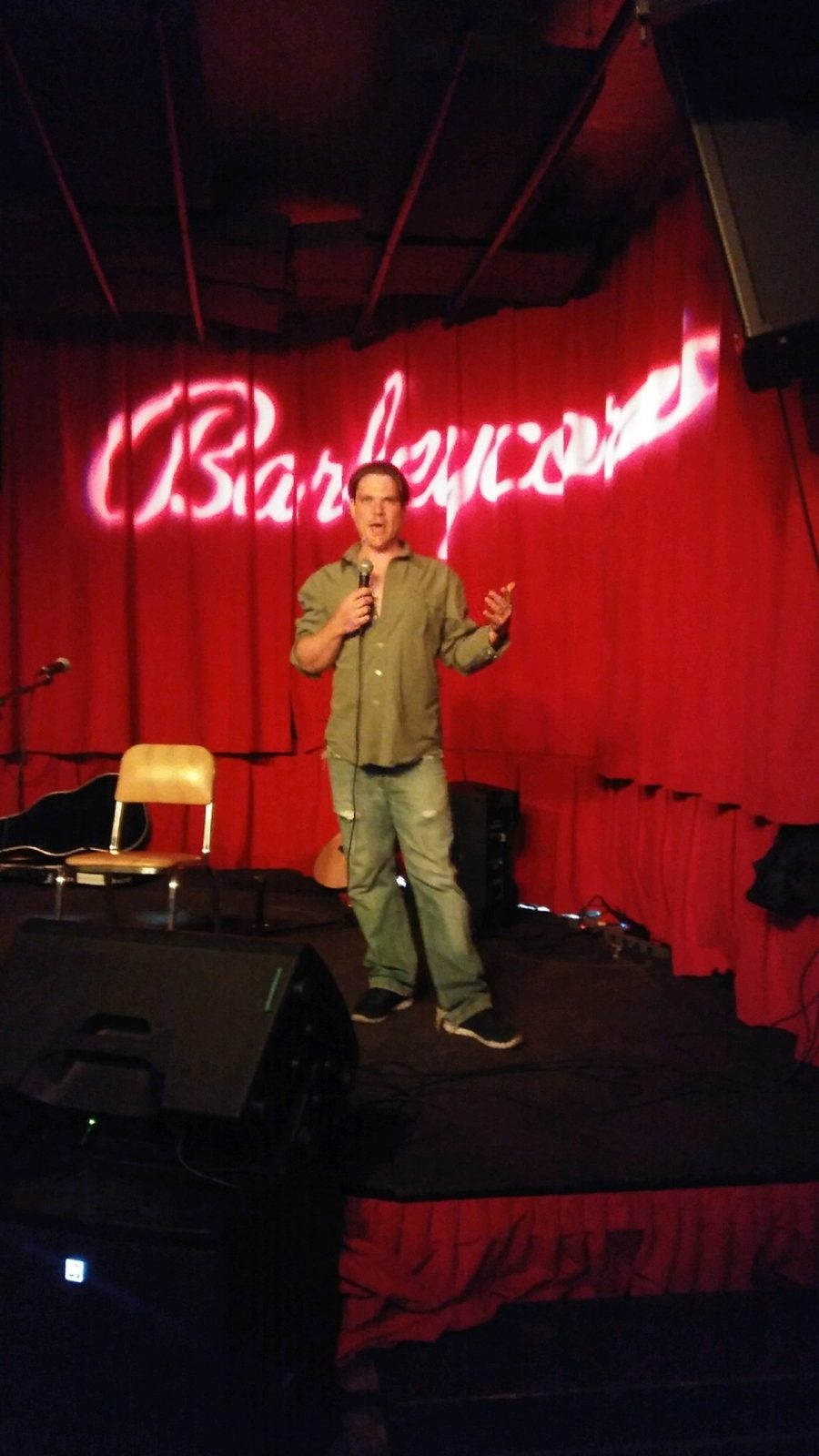 Bam performing in front of a red curtain and neon sign
