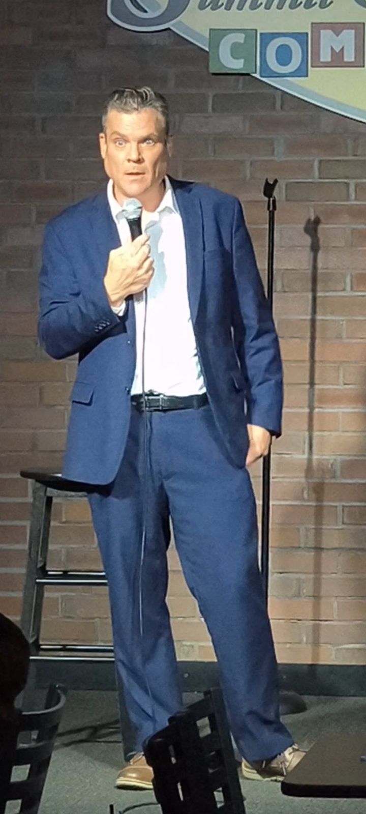 Bam in a suit on stage at Summit City Comedy